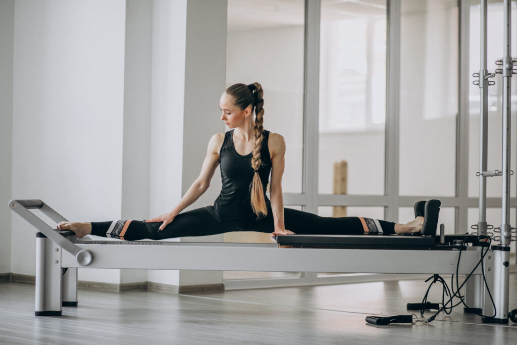 Woman practicing Pilates in a Pilates reformer.